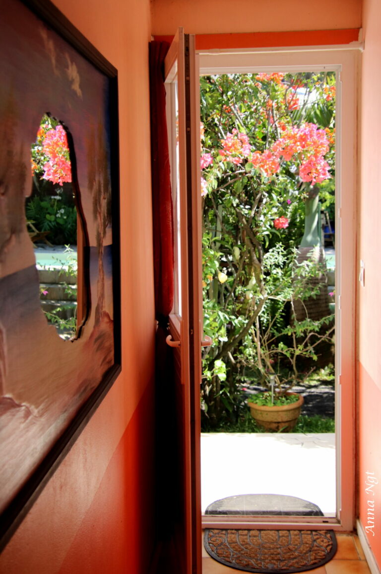 La porte d’une chambre ouverte sur le jardin fleuri de bougainvilliers
