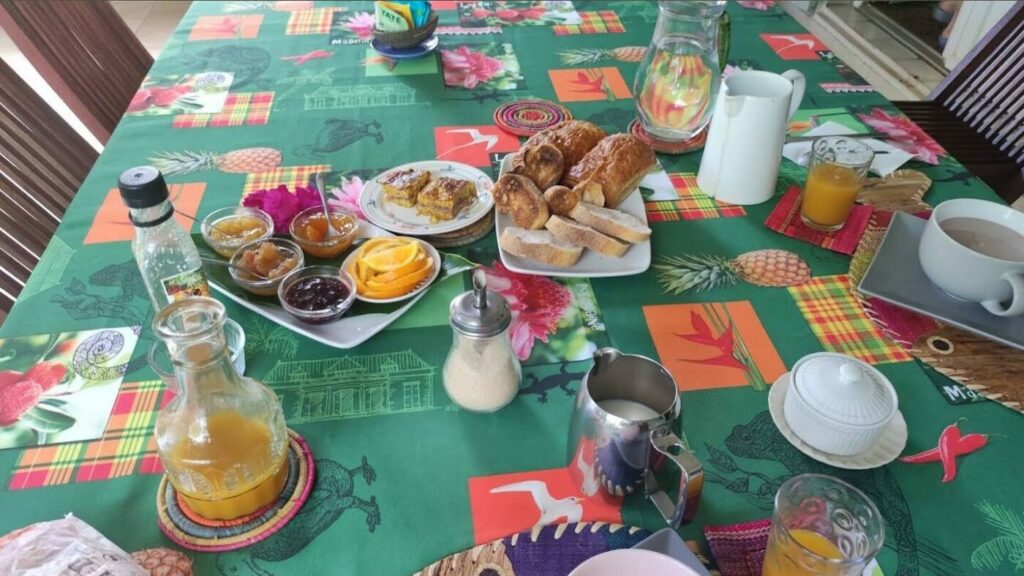 Petit déjeuner servi sur la nappe madras : confitures maison, brioche, pain frais, jus et café