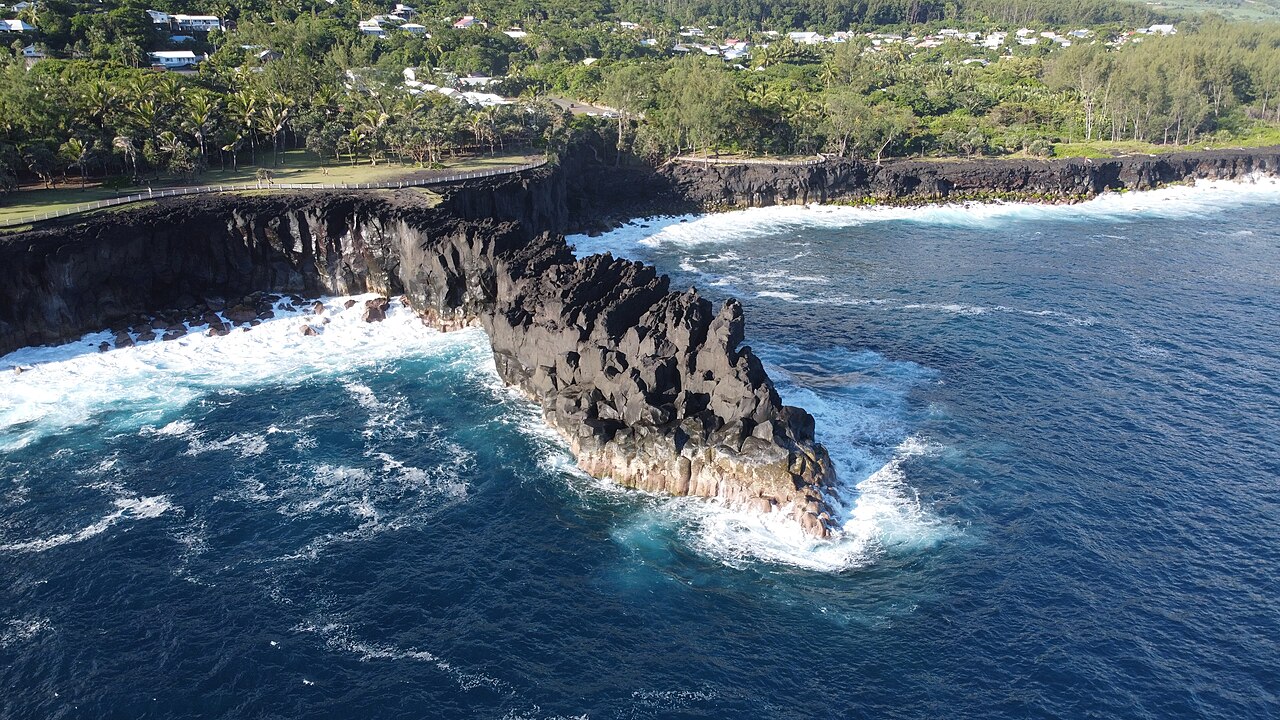 Les falaises de lave noire du Cap Méchant battues par l’océan, vues du ciel