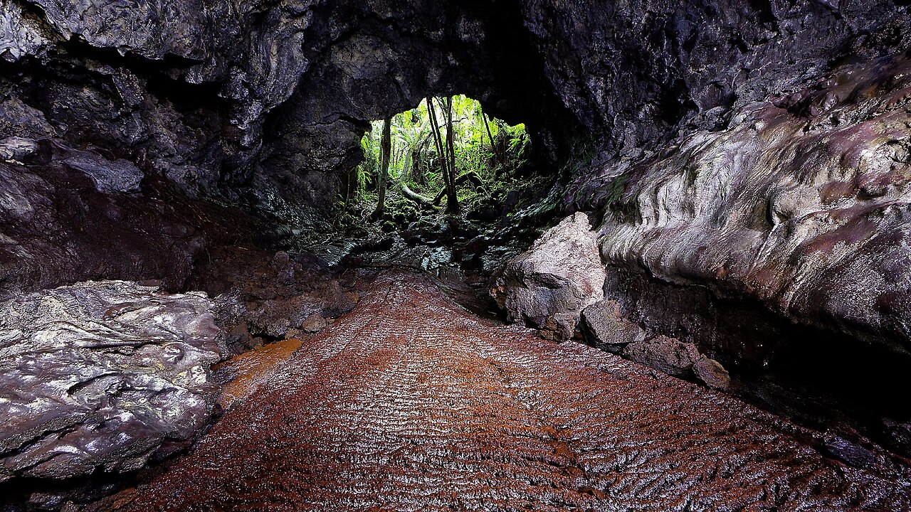L’intérieur d’un tunnel de lave à Saint-Philippe : sol de lave figée, sortie vers la végétation